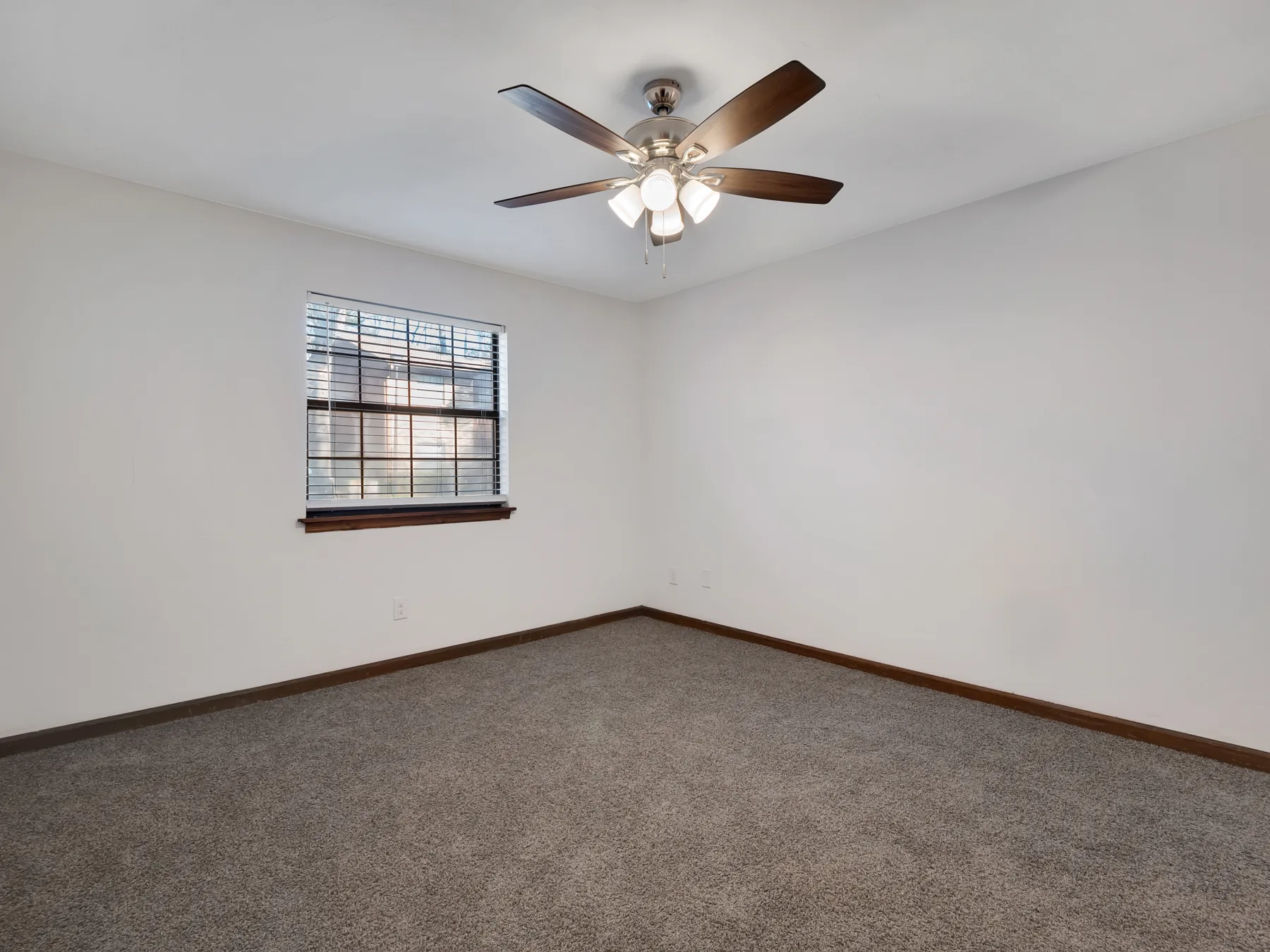 Carpeted bedroom with ceiling fan and window at Castle Apartments