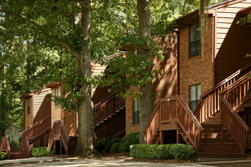 Brick two-story apartment building with exterior stairs and mature trees at Castle Apartments, Tallahassee