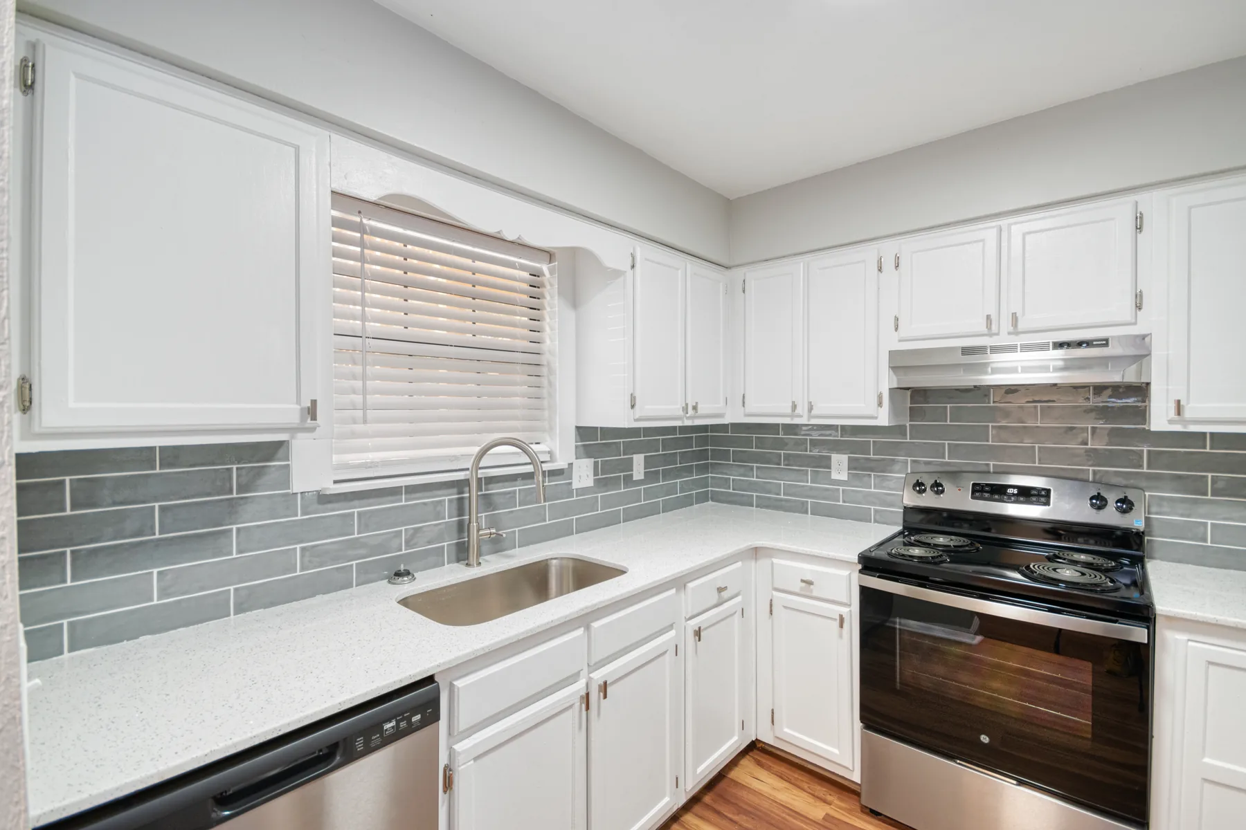 Kitchen with gray subway tile backsplash, white cabinets and stainless range at Castle Apartments
