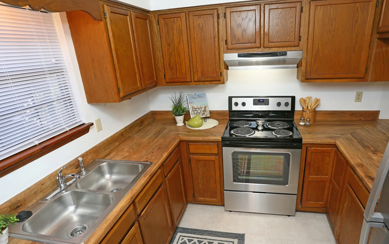 Classic kitchen with oak cabinets, butcher-block style counters and stainless range at Castle Apartments
