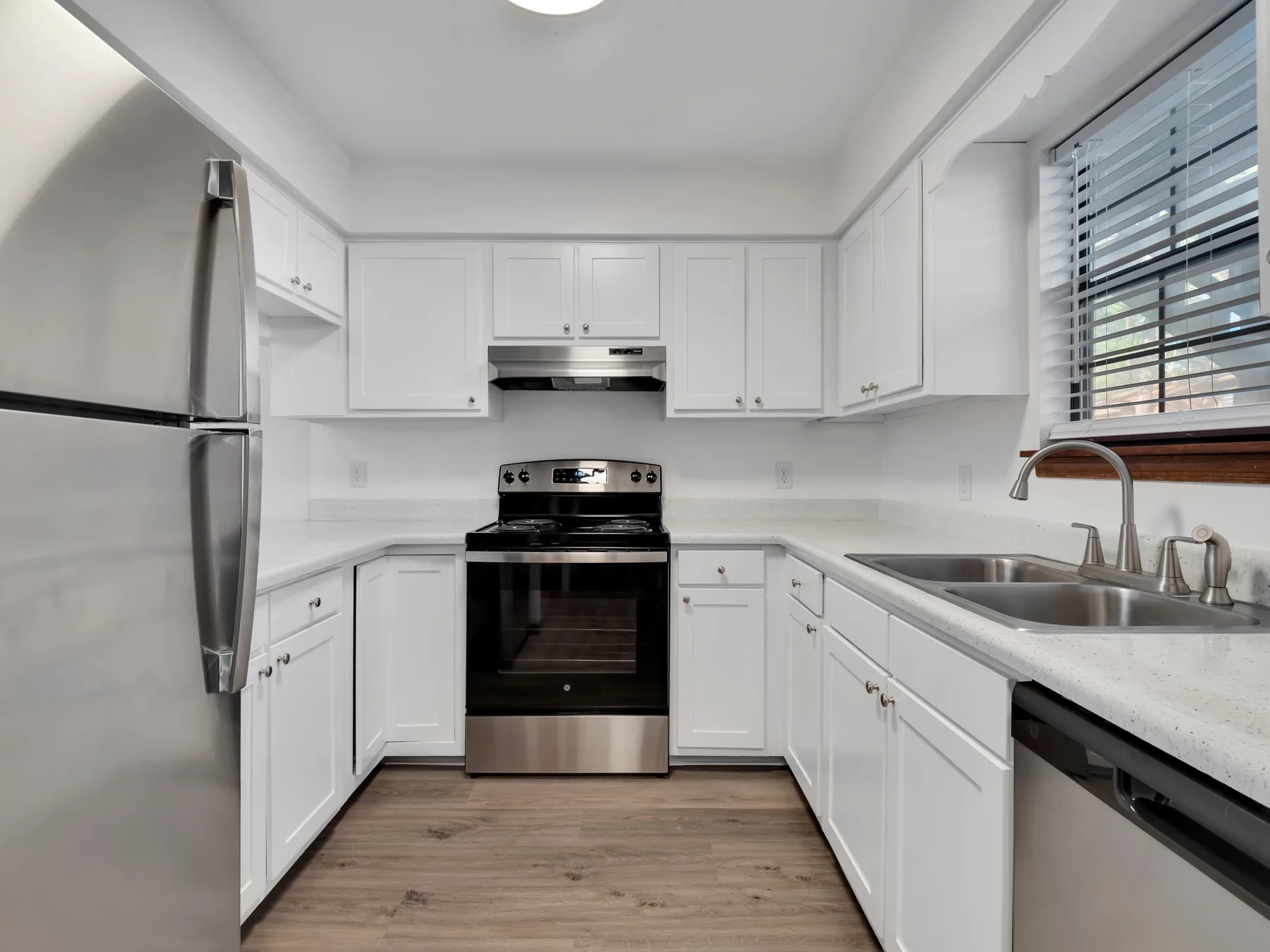 Kitchen with white cabinets, stainless steel refrigerator, range and dishwasher at Castle Apartments