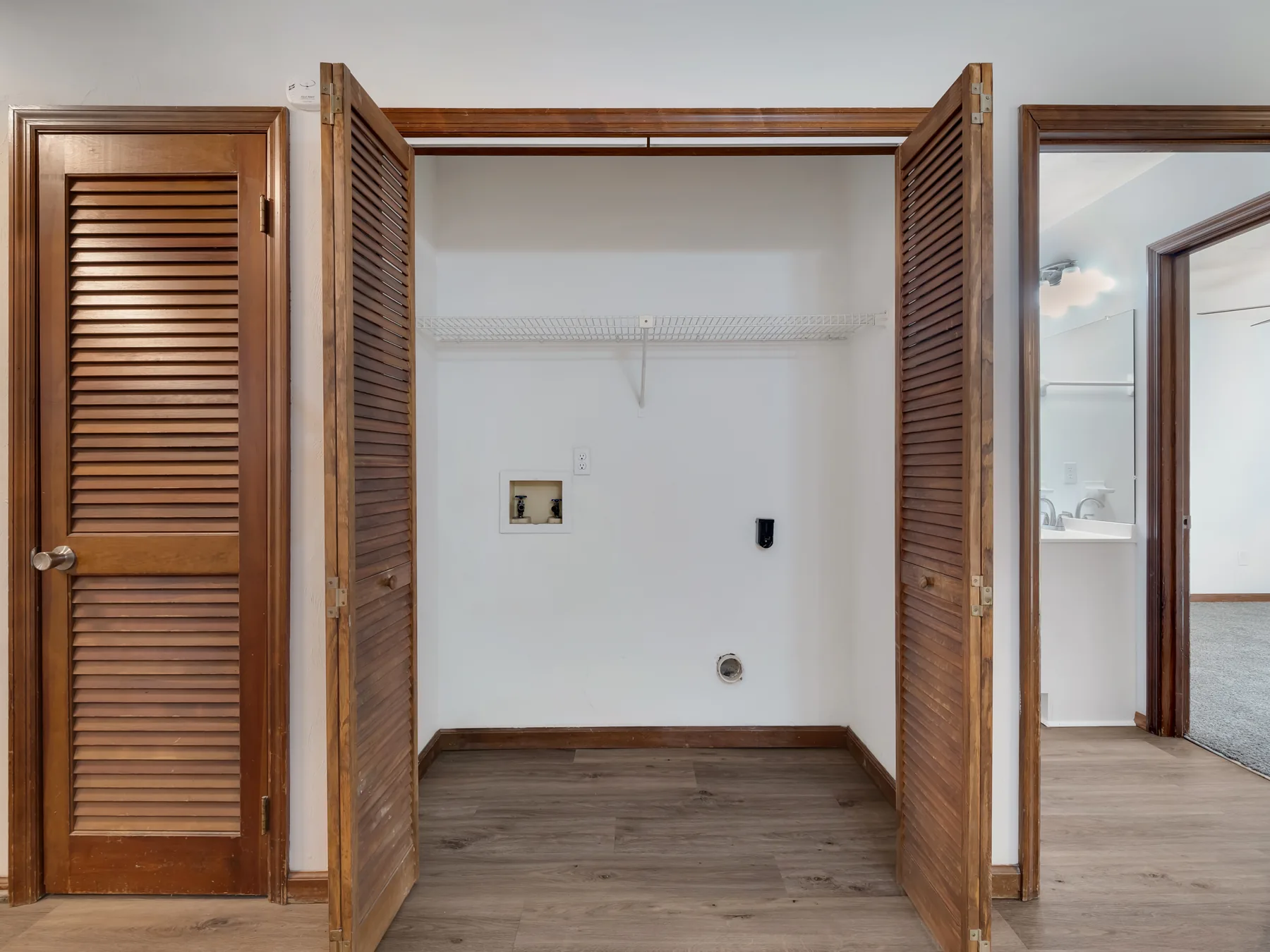 Laundry closet with full-size washer and dryer hookups behind louvered doors at Castle Apartments