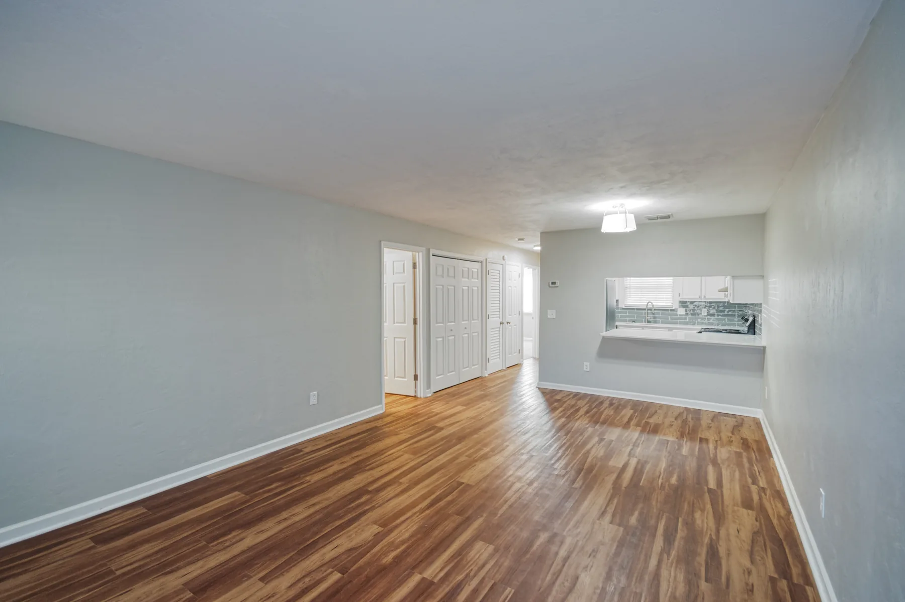 Living and dining area with wood-style flooring and pass-through to the kitchen at Castle Apartments